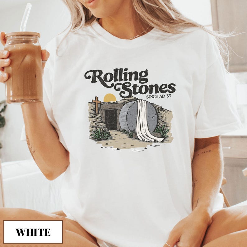May include: White t-shirt with a graphic of a stone tomb with a white sheet draped over it. The text "Rolling Stones Since AD 33" is above the tomb.