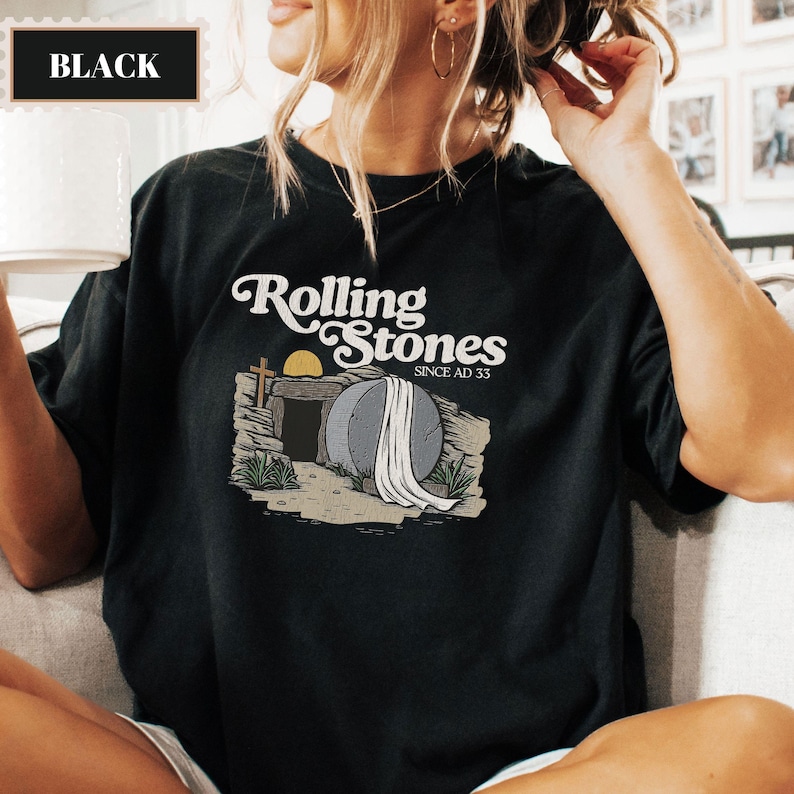 May include: Black t-shirt with a graphic of a stone tomb with a white sheet on top. The text "Rolling Stones Since AD 33" is above the tomb.