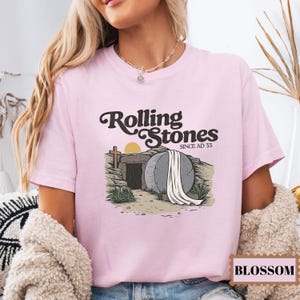 May include: Pink t-shirt with a graphic of a stone tomb with a white sheet and the text "Rolling Stones Since AD 33".
