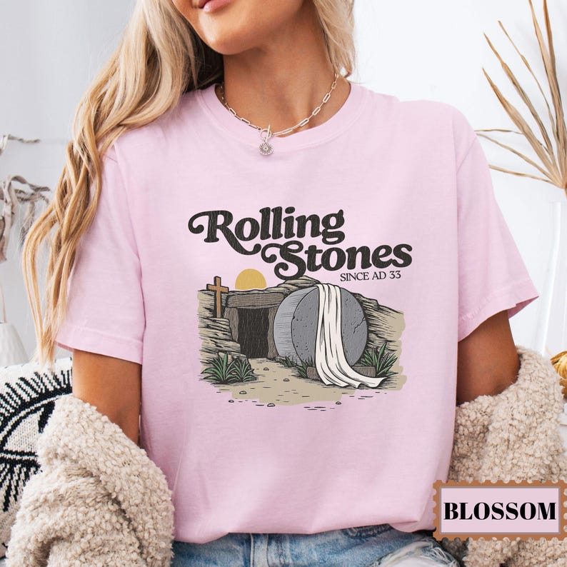 May include: Pink t-shirt with a graphic of a stone tomb with a white sheet and the text "Rolling Stones Since AD 33".
