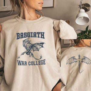 May include: A beige sweatshirt with a graphic of a dragon and the text "Basquiath War College".
