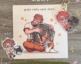 May include: A Project Hail Mary merchandise set featuring a square art print, a die-cut sticker, and an acrylic keychain. The artwork depicts a character with brown hair and glasses hugging a black geometric shape, with the text grace rocky save stars.