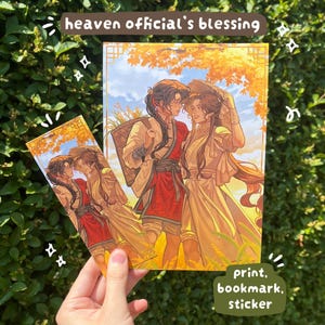 May include: A rectangular art print and a matching bookmark featuring an illustration of two characters in traditional robes with long dark hair, set against an autumn landscape. The text heaven official's blessing is at the top, with print, bookmark, sticker at the bottom.
