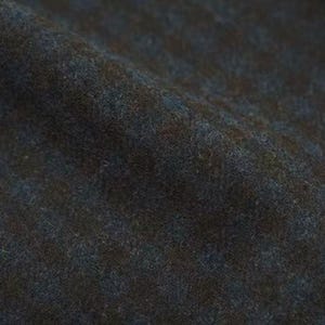 Può includere: Primo piano di un tessuto strutturato con un mix di fibre blu scuro, marroni e verdi. Il tessuto ha un aspetto morbido e leggermente sfocato, con sottili variazioni di colore e consistenza. Il materiale sembra essere un tessuto.