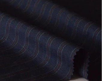 Puede incluir: Primer plano de tela azul marino con un sutil patrón ondulado. La tela tiene finas rayas verticales en un color más claro, con toques de rojo. El material parece ser un tejido, posiblemente para trajes o sastrería.
