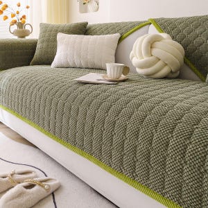K&ouml;nnte beinhalten: Eine gesteppte Sofahusse in Salbeigr&uuml;n mit limettengr&uuml;ner Paspel. Das Sofa ist mit dekorativen Kissen in Creme und Salbeigr&uuml;n geschm&uuml;ckt. Ein cremefarbenes Knotenkissen und eine Teetasse auf einer Untertasse sind ebenfalls zu sehen.