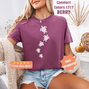 May include: Berry-colored t-shirt with a crew neck featuring a white turtle design. The shirt has the text "Comfort Colors 1717 BERRY" and a five-star review sticker that says "I love this shirt".