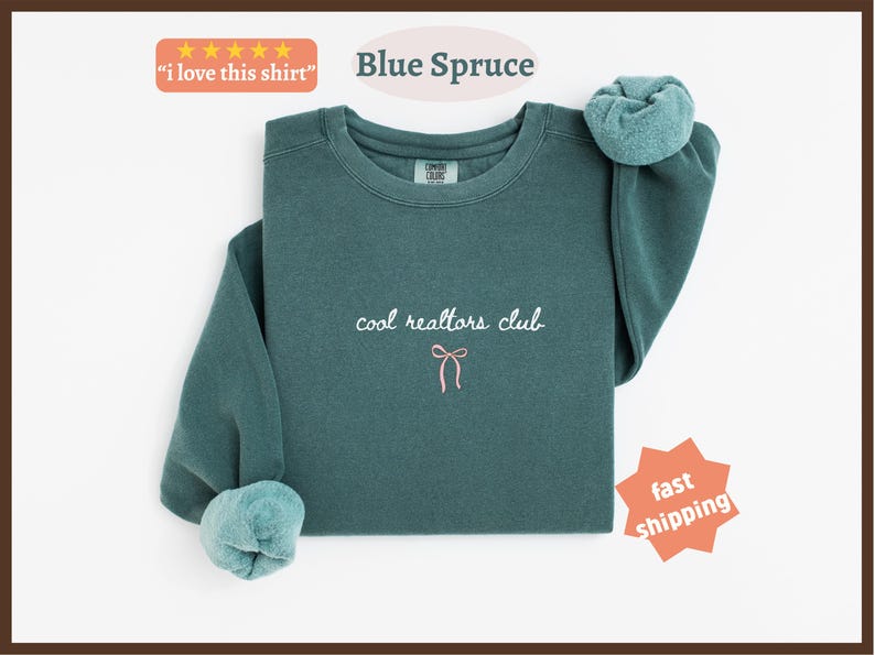 May include: A blue spruce colored crewneck sweatshirt featuring the embroidered white text "cool realtors club" centered on the chest, positioned above a small, simple pink line-art bow graphic. The garment has long sleeves with ribbed cuffs.