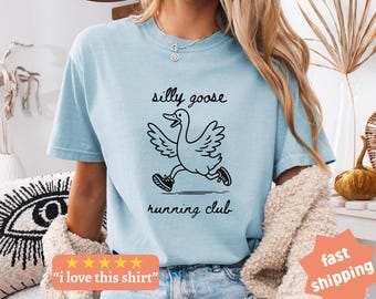 May include: Light blue t-shirt with a black graphic of a running goose and the words "silly goose running club". The shirt also has the text "I love this shirt" and "fast shipping".