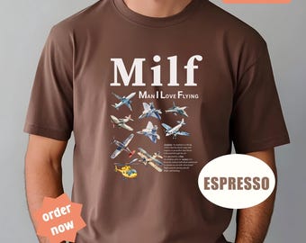 May include: Espresso-colored t-shirt with the word "Milf" in large white letters, with "Man I Love Flying" underneath. The shirt features various airplane illustrations. A sticker says "I love this shirt".