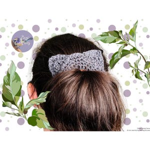 Könnte beinhalten: Ein graues gehäkeltes Haarschmuck-Accessoire in Form einer Schleife wird in einem Dutt getragen. Das Haar ist dunkelbraun. Der Hintergrund ist weiß mit grünen Blättern und lila Punkten. Der Text "Zuzi Creations" befindet sich in einem lila Kreis.