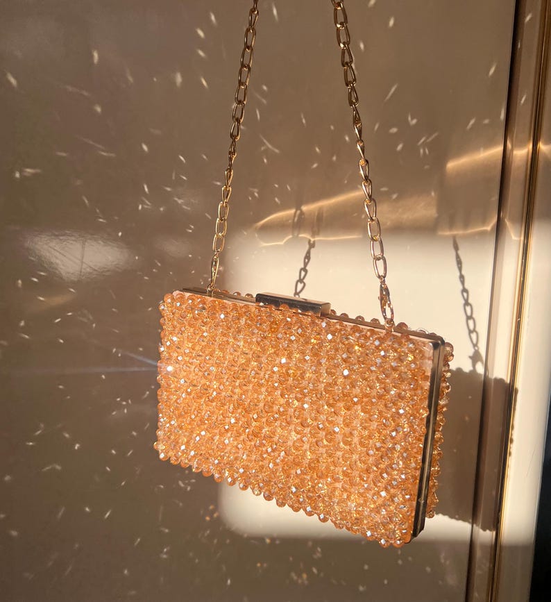 May include: A gold chain purse with a beaded clutch. The clutch is made of small, round, light brown beads.