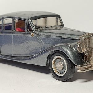 May include: A grey vintage car model with chrome accents. The car has a detailed interior and a classic design.