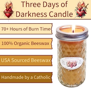 May include: A lit candle in a glass jar with a silver lid. The candle is labeled "Three Days of Darkness Candle" and includes text indicating 70+ hours of burn time, 100% organic beeswax, and USA sourced beeswax.