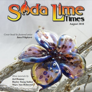May include: A magazine cover featuring a glass flower bead with iridescent purple, blue, and gold colours. The magazine title is "Soda Lime Times" with the subtitle "August 2018". The text "Silver Glass!" is displayed in large, orange letters at the bottom of the cover.