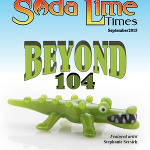 Könnte beinhalten: Das Cover des Magazins "Soda Lime Times", September 2015, zeigt eine grüne Glasalligator-Figur. Der Magazintitel ist in Orange und Gelb gehalten, mit dem Wort "BEYOND" in großen grünen Buchstaben. Die Nummer "104" steht darunter.