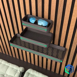 May include: Three dark gray wall-mounted trays of varying sizes, with dimensions of 18x8x3.5 cm, 20x11x3.5 cm, and 40x11x3.5 cm. The top tray holds blue-lensed sunglasses. The trays have a textured surface and are mounted on a wooden slatted wall.
