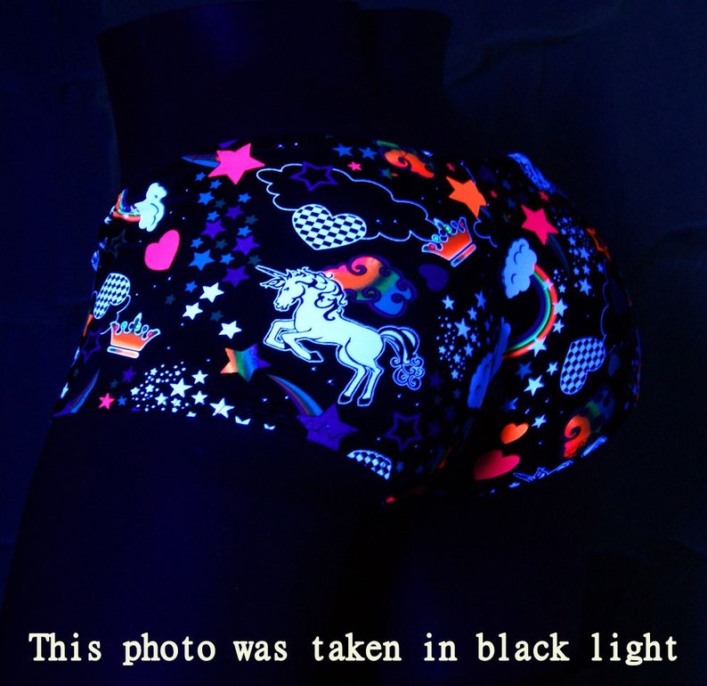 May include: Black shorts with a neon unicorn, stars, hearts, and rainbows design. The shorts are glowing under a black light.