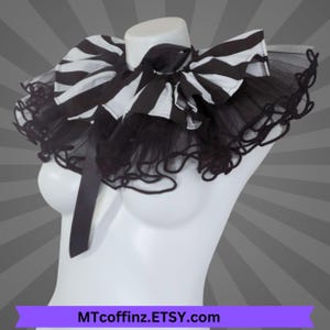 May include: A black and white striped bow collar with a black tulle trim, displayed on a white mannequin. The collar has a large bow and a satin ribbon. The Etsy shop name MTcoffinz.ETSY.com is visible at the bottom.