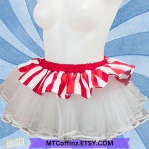 May include: A white tulle skirt with a red and white striped ruffle around the waist. The skirt is layered and has a ruffled hem. The text "MTCoffinz.ETSY.COM" is printed on the bottom of the image.
