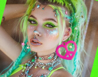 May include: A woman with bright green hair and colorful makeup is wearing a variety of necklaces and a pink peace sign heart earring. The text "MTCoffinz.ETSY.COM" is visible in the bottom right corner of the image.