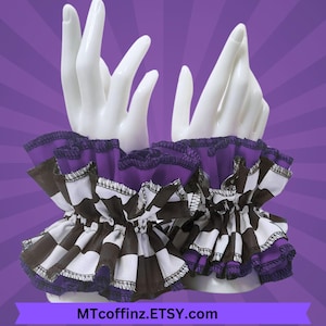 May include: A pair of ruffled wrist cuffs with a black and white checkered pattern, accented with purple fabric and trim. The cuffs are displayed on a white hand mannequin against a purple background. The text "MTcoffinZ.ETSY.com" is visible.