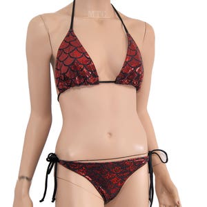 May include: Red and black bikini with a mermaid scale pattern. The top is a halter style and the bottom is a tie-side style.