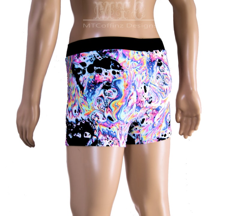 Puede incluir: Pantalones cortos tipo b&oacute;xer con un vibrante patr&oacute;n arremolinado en tonos rosa, azul, amarillo y negro. Los pantalones cortos tienen una cintura negra y un dise&ntilde;o abstracto colorido. El texto "MTCoffinz Design" es visible en la parte superior.