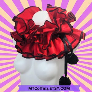 May include: A red ruffled collar with black trim and two black pom-poms on a black ribbon.  The collar is on a white mannequin bust.  MTCoffinz.ETSY.COM