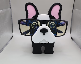 Könnte beinhalten: Eine schwarze und weiße Bulldoggen-Figur, die eine schwarze Brille mit gelbtönenden Gläsern trägt. Die Figur ist aus Kunststoff und hat einen Comic-Stil.