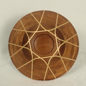 May include: A wooden bowl with a geometric design inlaid with gold. The bowl is made of dark wood and has a smooth, polished finish.