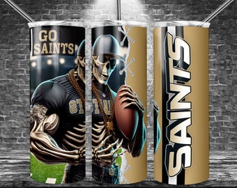 May include: A black and gold tumbler with a skeleton football player wearing a jersey with the number 21 and the word "Saints" on it. The tumbler has a gold background with the word "Saints" written in black and white.