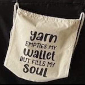 May include: A white drawstring bag with the text "yarn empties my wallet but fills my soul" printed in black.