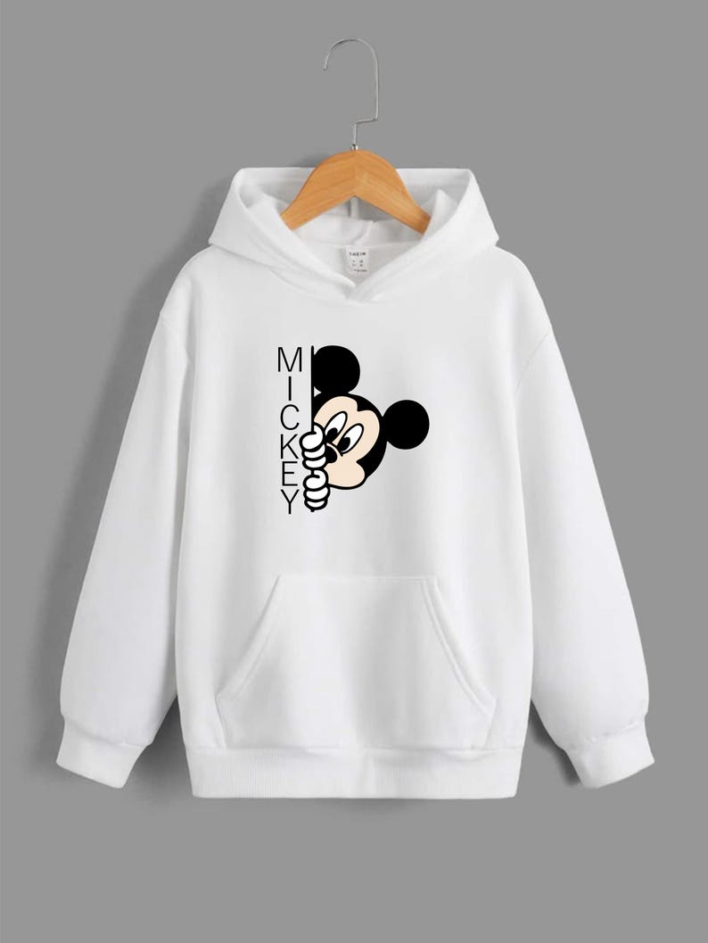Puede incluir: Sudadera con capucha blanca con un gr&aacute;fico de Mickey Mouse en blanco y negro que asoma por detr&aacute;s de la palabra "MICKEY".