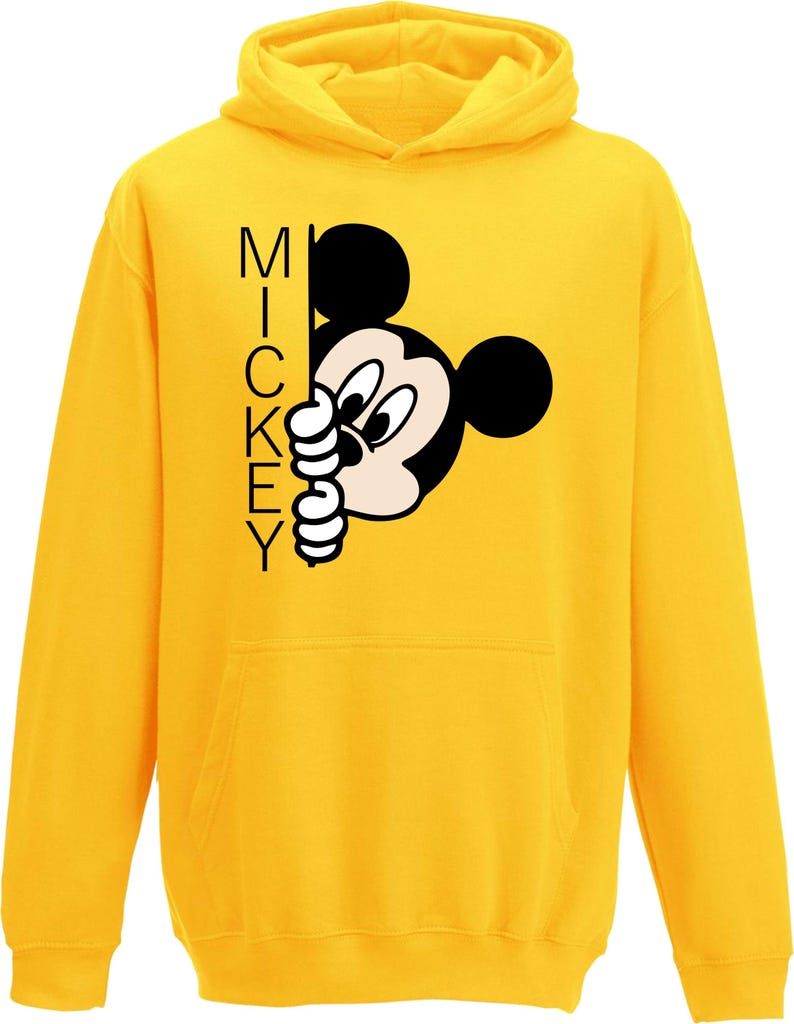 Puede incluir: Sudadera amarilla con capucha con una imagen de dibujos animados en blanco y negro de Mickey Mouse asom&aacute;ndose por una esquina. El texto "MICKEY" est&aacute; impreso verticalmente en el lado izquierdo de la imagen.