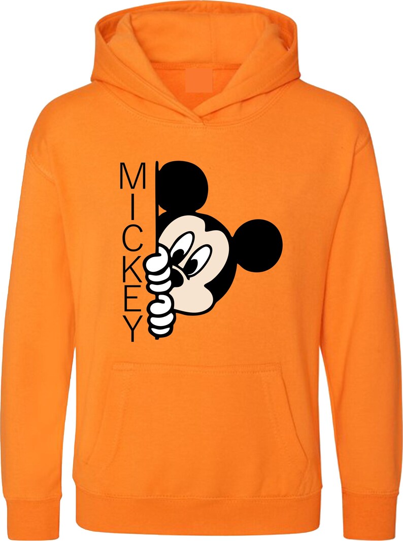 Puede incluir: Sudadera con capucha naranja con un gr&aacute;fico de Mickey Mouse en blanco y negro que asoma por detr&aacute;s de la palabra "MICKEY".