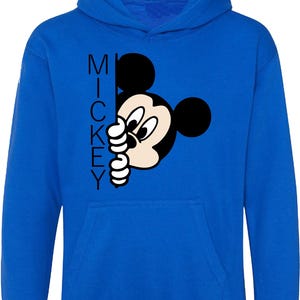 Puede incluir: Una sudadera con capucha azul real con una ilustraci&oacute;n en blanco y negro de Mickey Mouse asom&aacute;ndose por la esquina. La palabra "MICKEY" est&aacute; impresa verticalmente en el lado izquierdo de la imagen.