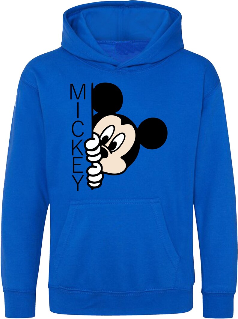 Puede incluir: Una sudadera con capucha azul real con una ilustraci&oacute;n en blanco y negro de Mickey Mouse asom&aacute;ndose por la esquina. La palabra "MICKEY" est&aacute; impresa verticalmente en el lado izquierdo de la imagen.