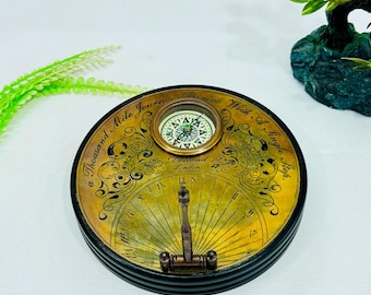 Reloj de mesa decorativo con brújula y esfera solar de aspecto antiguo, con números romanos, acabado en latón, ideal para la decoración de escritorio o como instrumento clásico de navegación para viajeros.