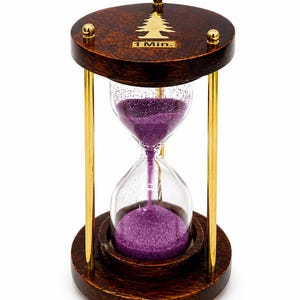 May include: A wooden hourglass with a dark brown finish and gold-colored metal accents. The hourglass contains purple sand and is designed to measure one minute. The top of the hourglass has a gold tree design and the text "1 Min."
