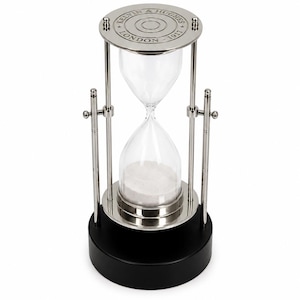 May include: A silver-toned metal hourglass with a clear glass bulb containing white sand. The top plate is engraved with the text KELVIN & HUGHES LONDON 1917. The frame features vertical support rods and rests on a solid black circular base.