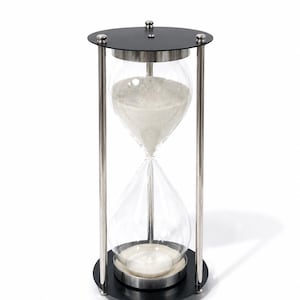 May include: An hourglass featuring a clear glass bulb filled with white sand, held within a frame of four vertical silver-toned metal rods. The structure is capped by circular black plates at the top and bottom, secured with small silver-toned metal knobs.