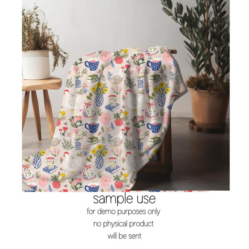 May include: A beige blanket featuring a repeating pattern of flowers, teacups, books, vases, and chickens. The flowers are pink, yellow, and red. The teacups are blue with white polka dots. The blanket is draped over a wooden chair.