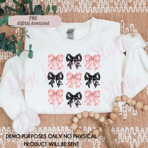 May include: A white sweatshirt with a design of nine pink and black bows with ghost patterns. The bows are arranged in three rows of three. The text "PNG digital download" is in the top left corner of the image.