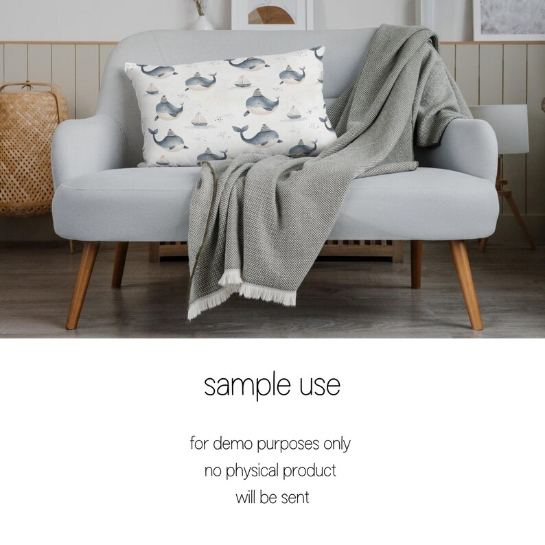 May include: A light gray sofa with a gray throw blanket and a white pillow with a watercolor pattern of blue whales and sailboats. The sofa has wooden legs.