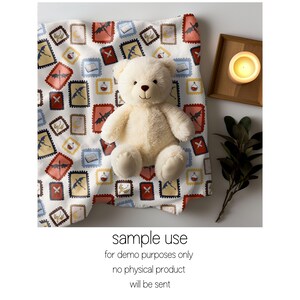 May include: A cream-colored teddy bear sits on a white fabric patterned with colorful postage stamp designs. The stamps feature dragons, books, and potion bottles. A lit candle in a wooden tray and greenery are also present. Text on the image reads: "sample use for demo purposes only no physical product will be sent."