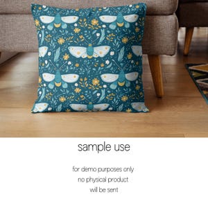 May include: A teal blue throw pillow with a repeating pattern of white butterflies and yellow flowers. The pillow is on a brown couch.