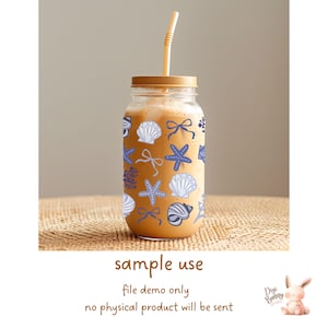 May include: A clear glass jar with a brown lid and a straw, filled with a light brown liquid. The jar is decorated with a pattern of blue and white seashells, starfish, and bows.