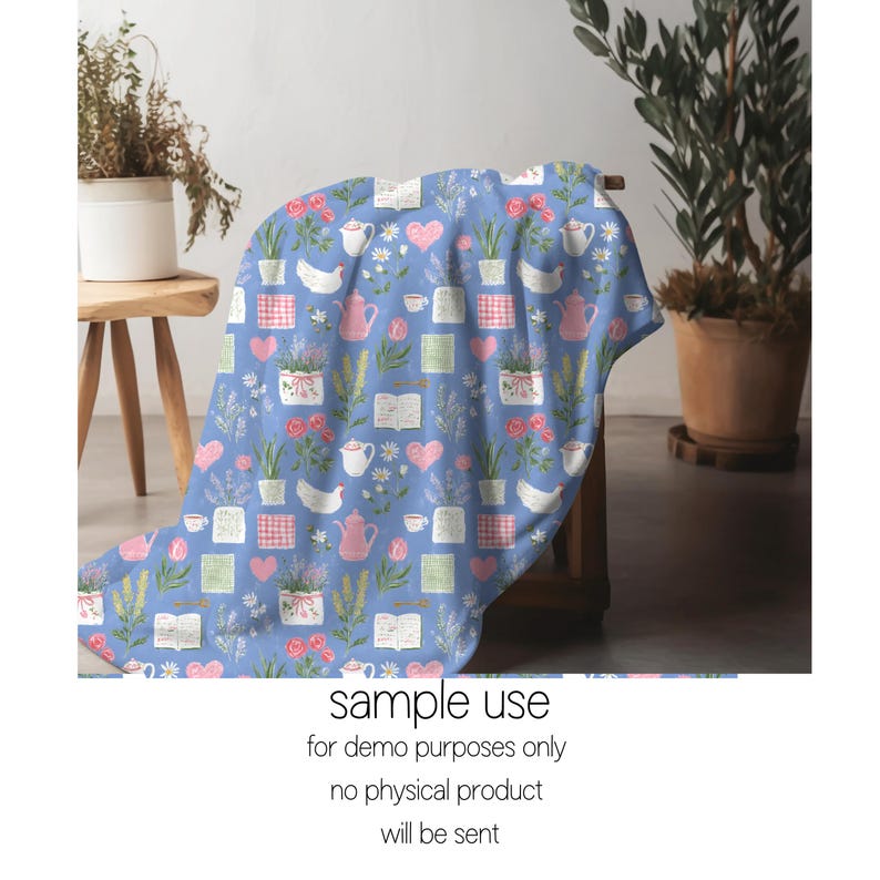 Pode incluir: Um cobertor azul com um padr&atilde;o repetido de bules rosa, cora&ccedil;&otilde;es, flores, livros e plantas em vasos. O cobertor est&aacute; sobre um banco de madeira. O texto "sample use for demo purposes only no physical product will be sent" est&aacute; na parte inferior.
