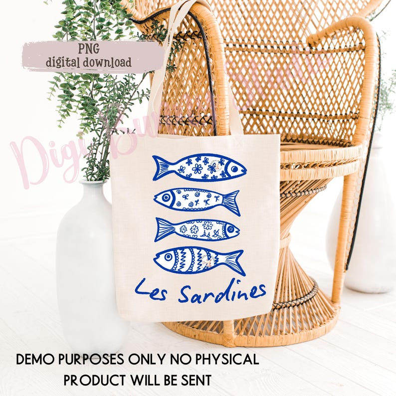 May include: A beige tote bag featuring four blue fish illustrations with decorative patterns. The words "Les Sardines" are written in blue script below the fish. The bag is set against a wicker chair and white vase.